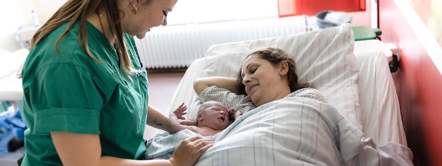 Elterninfoabend Hebamme legt Mama das frisch geborene Baby an die Seite