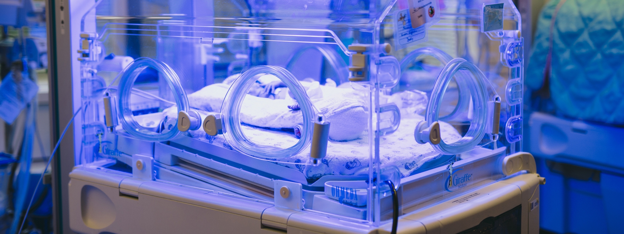 Frühgeborenes Baby im blau beleuchteten Inkubator