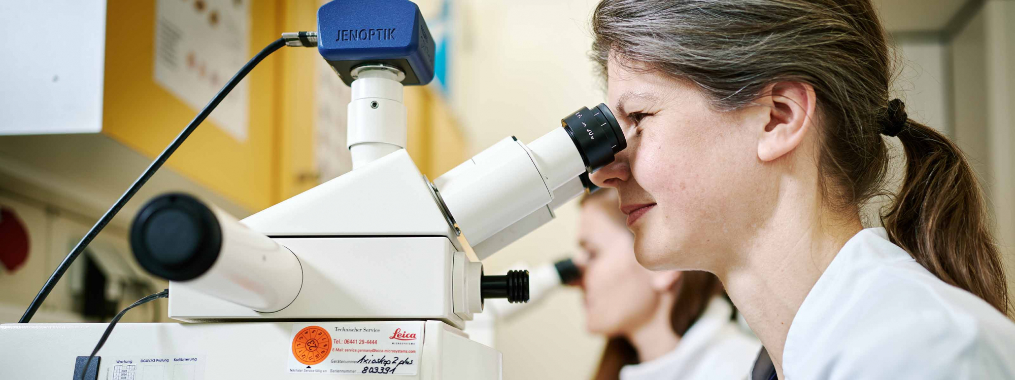 Zwei Ärztinnen schauen im Labor durch das Mikroskop