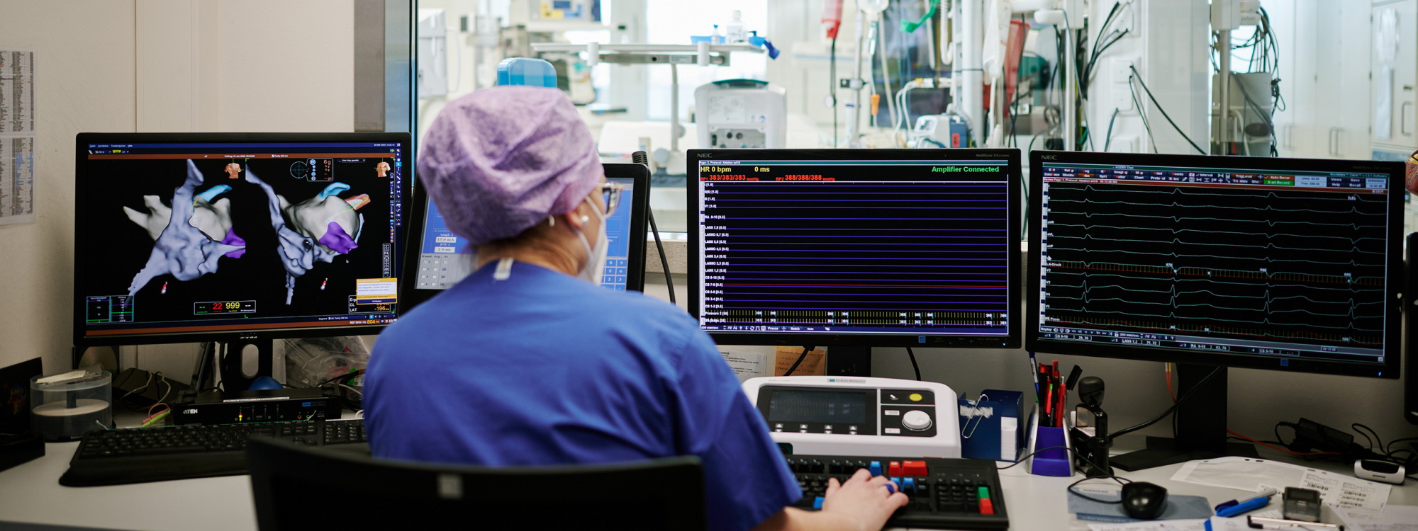 Mitarbeiterin sitzt mit dem Rücken zu uns und schaut sich die Krankheitsbilder auf dem Monitor an