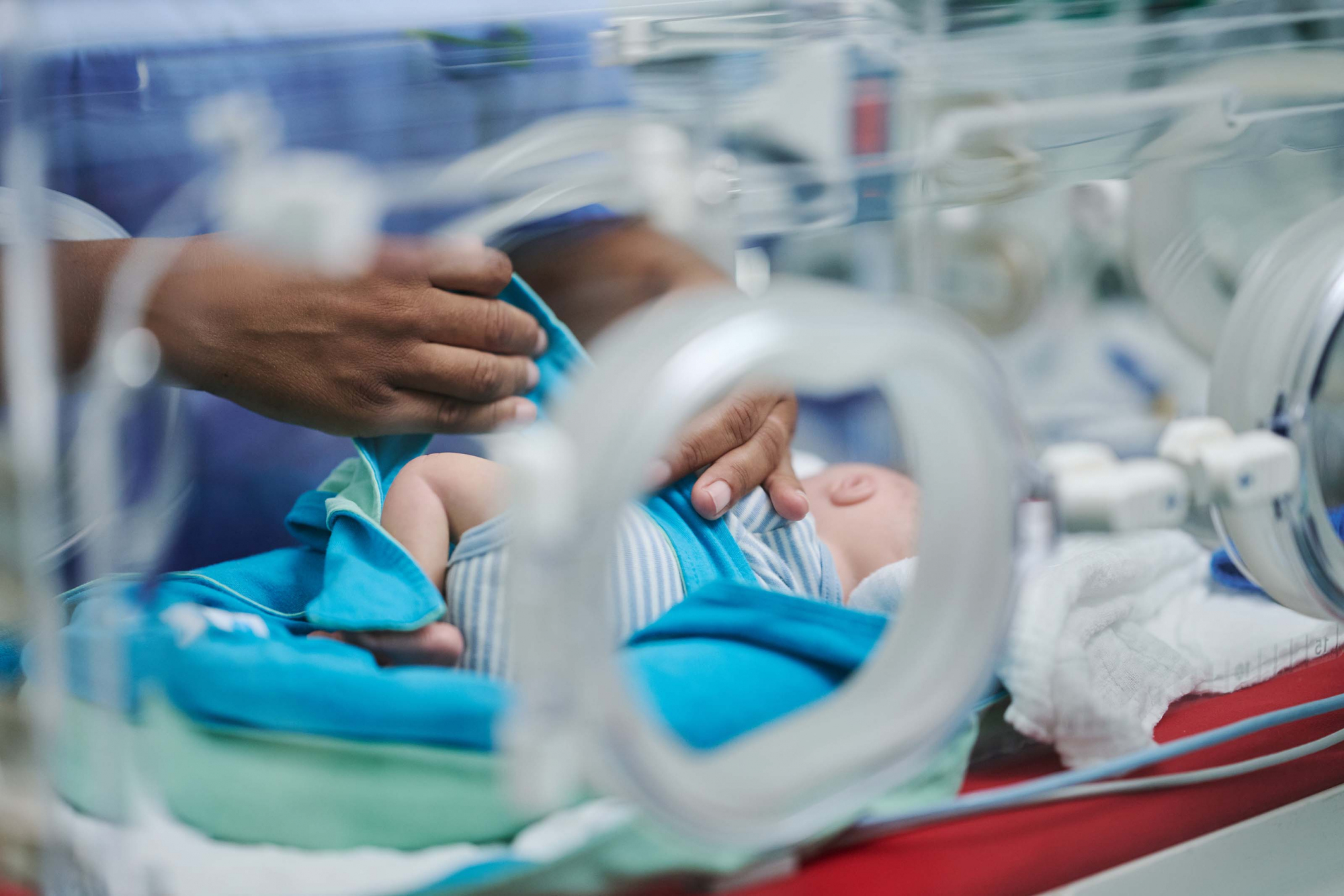 Pflegekraft versorgt frühgeborenes Baby, das im Inkubator liegt